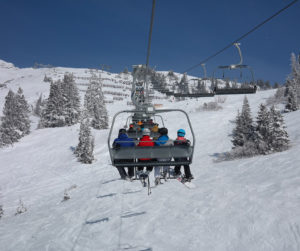 group on ski lift over snowy mountain
